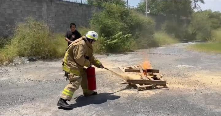 Brigadista con equipo de bombero sofocando fuego con un extintor