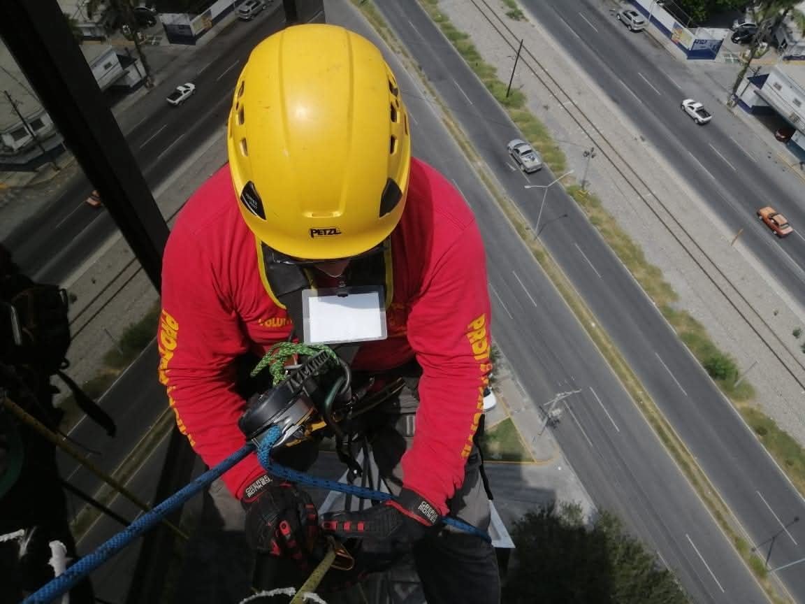 Rescatista con casco amarillo en descenso controlado sobre avenida