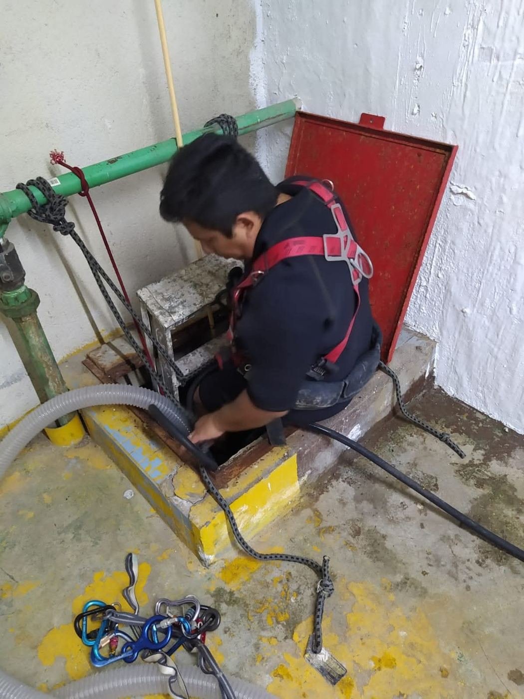 Técnico con arnés ingresando a un espacio confinado