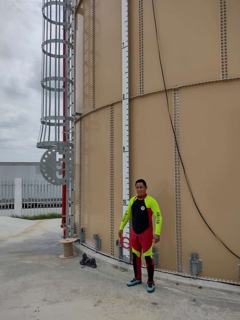 Técnico con equipo de protección junto a un tanque de almacenamiento