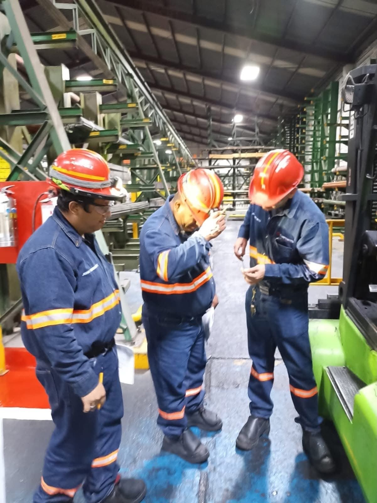 Personal con casco y uniforme reflejante en inspección dentro de planta