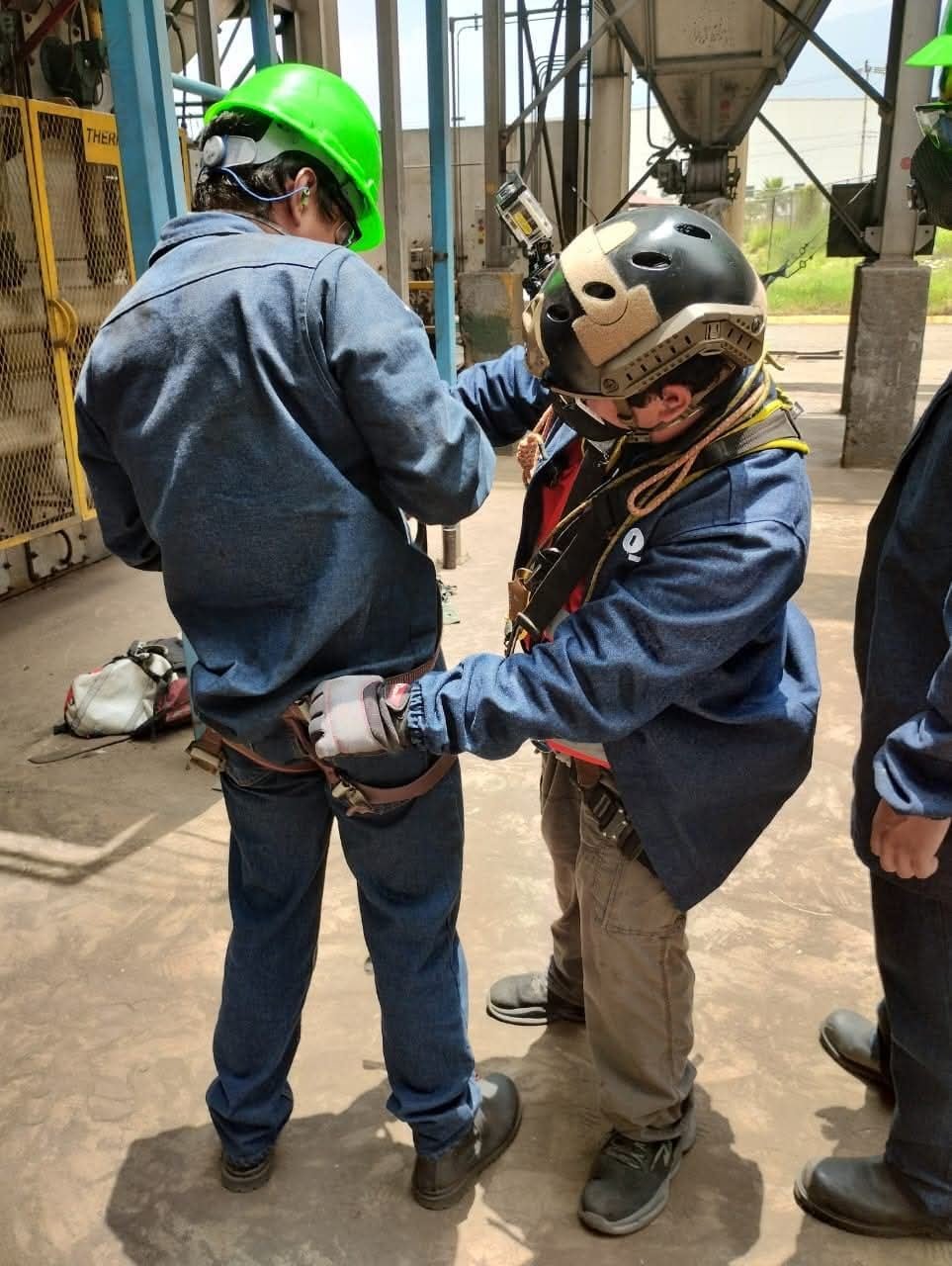 Instructor revisando el arnés de un trabajador